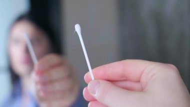 Kulak temizliği için pamuklu bez tutan genç bir kadın enfeksiyon ve iltihaplanmayı önlemek için kulak bakımı, kişisel hijyen rutini. Yüksek kalite 4k görüntü
