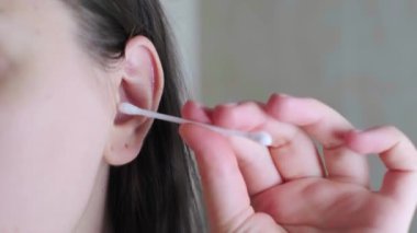 Kulağını pamuklu çubukla temizleyen bir kadın eli, kulak hijyeni ve güvenli temizlik aletleri için kişisel bakım ürünleri. Yüksek kalite 4k görüntü