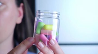 Renkli kulak tıkaçlarıyla dolu bir kutu tutan bir kadın, çevre dostu ve güvenli, tahriş etmeyen, kaliteli bir uyku için yüzde yüz ses emici. Yüksek kalite 4k görüntü
