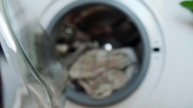 Çamaşırcı kadın çamaşır makinesinden temiz çamaşırları çıkarır ve çamaşır kurutma makinesinde kurulanmaya hazırdır. Yüksek kalite 4k görüntü