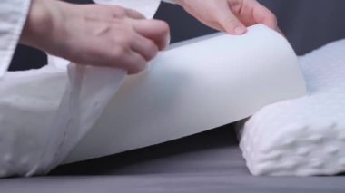 Bir kadın gri bir yatakta, hafızalı köpük bir yastığın üzerinde süzülür, rahat bir uyku ve sağlıklı bir omurga için ortopedik bir yastık sergiler. Yüksek kalite 4k görüntü