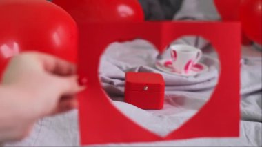 Sevgililer Günü kahvaltısı kalp şeklinde balonlarla süslenmiş bir yatakta hediye ile aşk ve neşeyi kutluyoruz. Yüksek kalite 4k görüntü