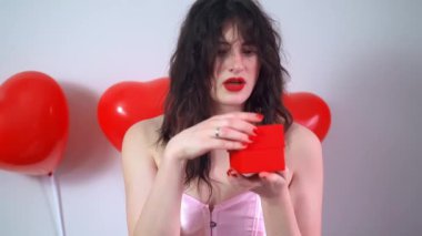 Sevgililer Günü 'nde bir kadın sevgilisine bir elinde bir kutu diğer elinde kalp şeklinde bir balon tutarak bir hediye hazırladı. Yüksek kalite 4k görüntü