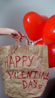 Gri bir arka planda, üzerinde kalp şeklinde balonlar olan bir Sevgililer Günü hediye paketi. Aşkı ve kutlamayı simgeliyor. Yüksek kalite 4k görüntü