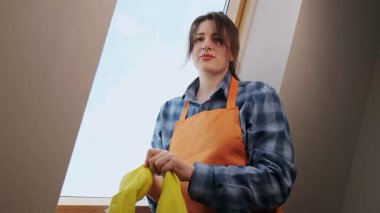 Temizlik kıyafetleri içindeki kadın, ev temizliği işleri için lastik eldiven takarak işe hazırlanıyor. Yüksek kalite 4k görüntü