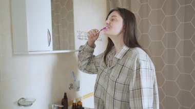 Genç bir kadın aynanın önünde diş hijyenine önem verir. Parlak bir gülümseme, düzenli fırçalama diş minelerinin sararmasını önler. Yüksek kalite 4k görüntü