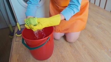 Bir kadın yerleri paspaslıyor ve yıkadıktan sonra bezleri sıkıyor. Profesyonel temizlik tertemiz ve taze bir ev sağlar. Yüksek kalite 4k görüntü