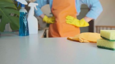 Arka planda temizlik uzmanı olan mutfak masasındaki temizlik ürünleri kollarını kavuşturup göreve hazır olduğunu gösteriyor. Yüksek kalite 4k görüntü
