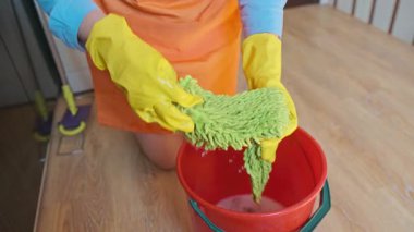 Bir hizmetçi evi temizliyor, kovadan bir bez çıkarıyor. Güvenli ve etkili bir temizlik işlemi için temizlik ürünlerini kullanmak. Yüksek kalite 4k görüntü