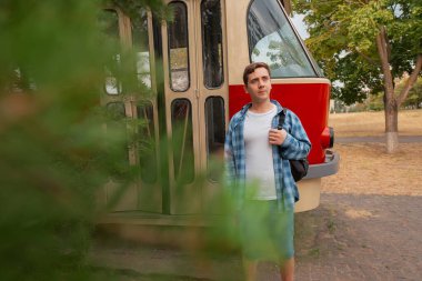 Hareket halinde: Sırt çantalı bir adam tramvay kapısında duruyor, yeni bir rota için hazır. Rahatlatıcı bir şehir kaçışı için hafif seyahat.