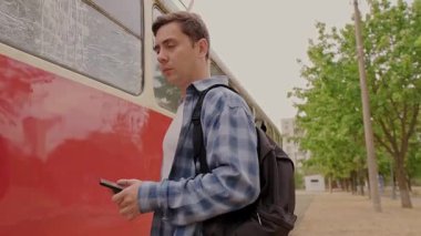Tren istasyonunda sırt çantalı bir adam, telefonunu platformu ve trenini bulmak için kullanıyor. Yüksek kalite 4k görüntü
