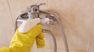 Evde temizlik rutini: koruyucu giysili ve eldivenli bir kadın lavaboya temizleyici sıkar, temizlik ürünleriyle yıkar. Yüksek kalite 4k görüntü