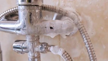 Temiz musluk ve musluk temizleme ürününden köpükle kaplı ve küvete köpük damlıyor. Yüksek kalite 4k görüntü