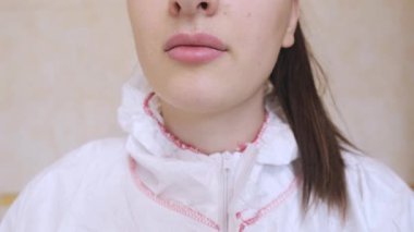 Koruyucu giysili kadın doktor, güvenliği sağlamak ve tedbirlere uymak için maske takarak işe hazırlanıyor. Yüksek kalite 4k görüntü