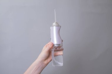 Bir kadının eli diş bakımı için bir su temizleyicisini tutar. İstikrarlı bir su akışı plağı kaldırmaya ve sakız sağlığını iyileştirmeye yardımcı olur..