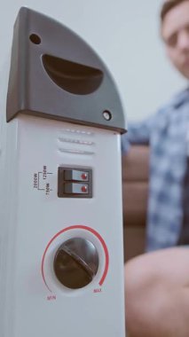 Bir adam kış boyunca evde üşüdüğünü hisseder ve ısınmak için elektrikli ısıtıcıyı açar. Yüksek kalite 4k görüntü