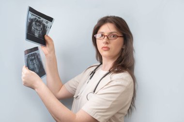 Kadın dişçi, hastanın röntgen görüntülerini karşılaştırarak hastalığın ilerlemesini değerlendirir..