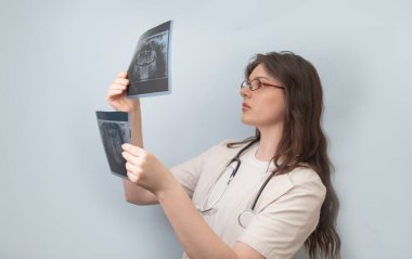 Kadın dişçi, hastanın iki röntgen görüntüsünü karşılaştırarak hastalığın ilerlemesini değerlendirir..