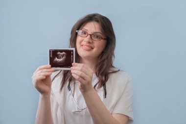 Kadın doğum uzmanı hamile bir kadının ultrason görüntüsüne sahip. Ona sağlık ve hamilelik konularında danışmanlık yapıyor..