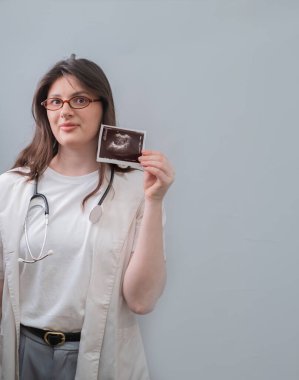 Kadın doğum uzmanı-jinekolog bir hastayla çalışıyor. Sağlıklı ve güvenli gebelik için ultrason görüntülerini analiz ediyor..