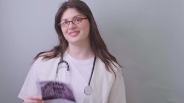 Kadın dişçi, hastanın iki röntgen görüntüsünü karşılaştırarak hastalığın ilerlemesini değerlendirir. Yüksek kalite 4k görüntü