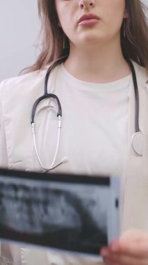 Kadın dişçi, hastaların diş durumlarındaki değişiklikleri değerlendirmek için iki röntgen görüntüsünü inceler. Yüksek kalite 4k görüntü