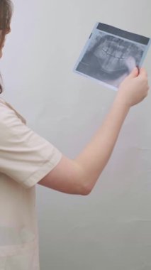 Deneyimli bir dişçi, hastaların diş durumlarını X-ray görüntüsüyle doğru teşhis için değerlendirir. Yüksek kalite 4k görüntü