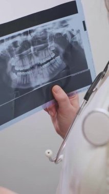 Kadın dişçi, değişimleri tespit etmek ve hasta için doğru bir teşhis koymak için iki röntgeni analiz eder. Yüksek kalite 4k görüntü