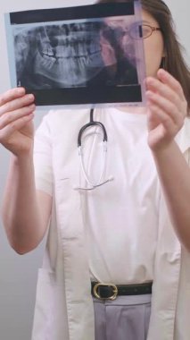 Diş hekimi, tedavi sürecini değerlendirmek ve potansiyel sorunları tespit etmek için röntgen görüntülerini karşılaştırıyor. Yüksek kalite 4k görüntü