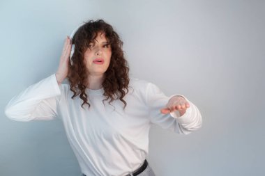 Kıvırcık saçlı enerjik DJ, kablosuz kulaklık takıyor, şarkı söylüyor ve dans ediyor..