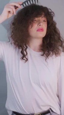 Sabah kendini sevme ile başlar: kıvırcık saçlı kadın buklelerini fırçalar ve kafa derisine rahatlatıcı bir masaj yapar. Yüksek kalite 4k görüntü