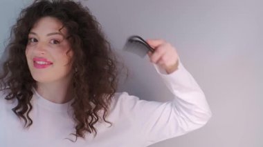 Kadın kıvırcık saçlarını tarıyor, kafa derisine masaj yapıyor ve sessizlikten ve kendine bakmaktan zevk alıyor. Yüksek kalite 4k görüntü