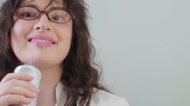 Sulama makinesiyle evde bakım. Pijamalı bir kadın dişçilerinin tavsiyelerine uyarak dişlerine dikkat eder. Yüksek kalite 4k görüntü