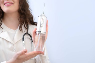 Kadın dişçi diş temizleyicisini gösterir ve aletin her parçasının ağız temizliğine nasıl yardımcı olduğunu açıklar..