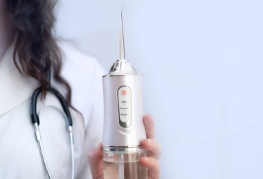 Diş hekimi, ağız temizliği için sulayıcının nasıl kullanılacağını anlatıyor..