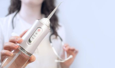 Ortodontist bir sulayıcı tutuyor ve diş çürüklerini ve diş eti iltihabını nasıl önlediğini anlatıyor..