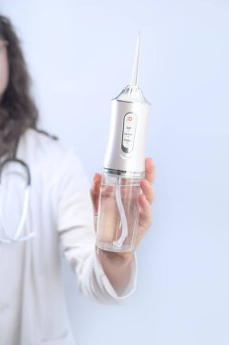 Kadın diş hekimi, ağız temizleyicisinin nasıl kullanılacağını ve günlük su temizliğinin neden oral sağlık için gerekli olduğunu açıklar..