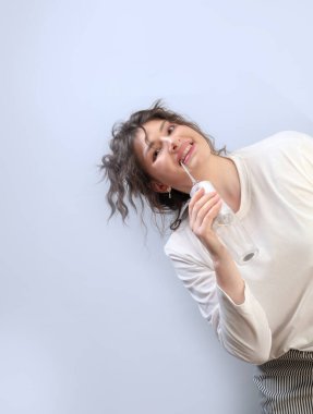 Yararlı sabah rutini: kadın diş hekiminin sağlıklı dişler için tavsiyeleri doğrultusunda su temizleyicisiyle plaketi çıkarır..