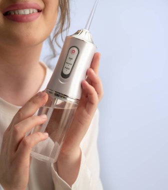 Güne temiz dişler ve taze bir başlangıç: kadın, yiyecek atıklarını ve plaketi bir su temizleyicisiyle temizliyor.