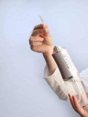 Modern ağız hijyeni: bir kadın diş sağlığını korumak için plakları ve yiyecek parçacıklarını temizlemek için sulayıcı kullanır.