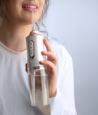 Diş hekiminin tavsiyesine göre kadın sağlıklı sabah rutininin bir parçası olarak dişlerini iyice temizlemek için diş ipi kullanıyor..