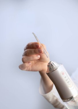 Elektrikli diş temizleyicisi: bir kadın diş çürüklerini önlemek ve diş temizliğini garantiye almak için evde kullanır.