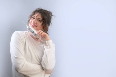 Güne temiz dişlerle başlayan kadın, sağlıklı bir gülümseme için yiyecek parçacıklarını ve plaketi temizlemek için su temizleyicisi kullanıyor.