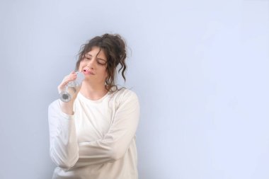 Genç bir kadın, sabahları günlük ağız temizliği için elektrikli su ipi kullanıyor. Evde diş bakımı rutini.