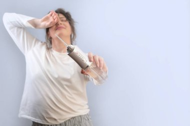 Pijamalı bir kadın dişlerini temizlemek için su temizleyicisi kullanıyor, sabah banyoda rutin bir iş. Evde kendine dikkat et..