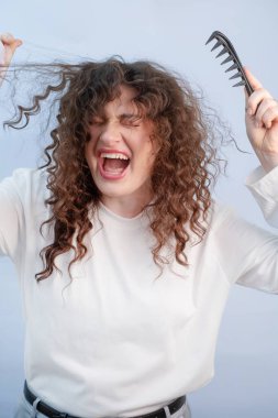 Kızcağız acıdan kıvranıyor. Yoğun ve kırılgan bukleleri çözmeye çalışıyor. Gereksiz bakım saç kırıntılarına ve şiddetli saç dökülmesine neden oluyor..