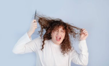 Genç kadın, kıvırcık saç bakımıyla mücadele eden ve zor saç sorunlarıyla başa çıkan güçlü bir rahatsızlık ve stres hissediyor..