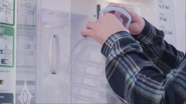 Şehir ortamındaki su otomatından gelen içme suyuyla plastik kabı dolduran adam. Pratik ve çevre dostu. Yüksek kalite 4k görüntü