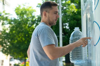 Kentsel ekoloji adamı, şişelenmiş su kullanmaktan kaçınmak için otomattan temiz su doldurmak için kişisel konteynır kullanır.