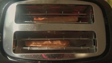 Ekmek dilimlenmiş ekmek kızartma makinesinin en üst görüntüsü bir dakika içinde mükemmel bir şekilde altın gibi ortaya çıkacak ve yemeye hazır olacak. Yüksek kaliteli FullHD görüntüler
